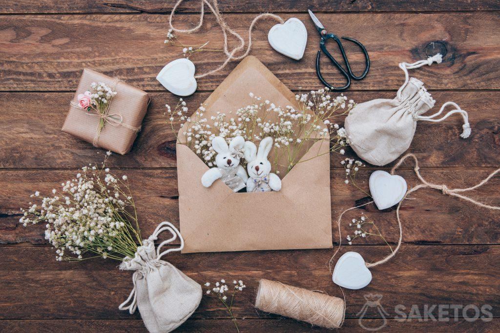 Un sac en lin avec un pansement, des lapins en peluche dans une enveloppe et un cadeau emballé dans du papier gris.