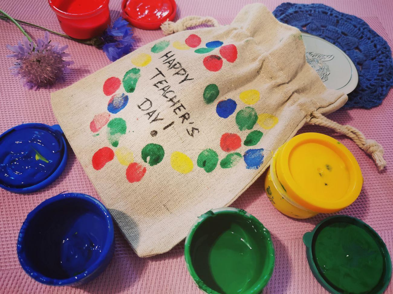 Un cadeau pour un enseignant dans un sac décoré des empreintes digitales de ses élèves
