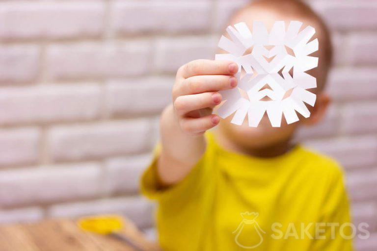 Enfant découpant un flocon de neige dans du papier