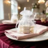 Décoration de table de mariage utilisant des sachets en organza blancs.