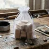 Sachet en organza 15x20 cm rempli de tampons en bois pour l'artisanat sur une table d'atelier.