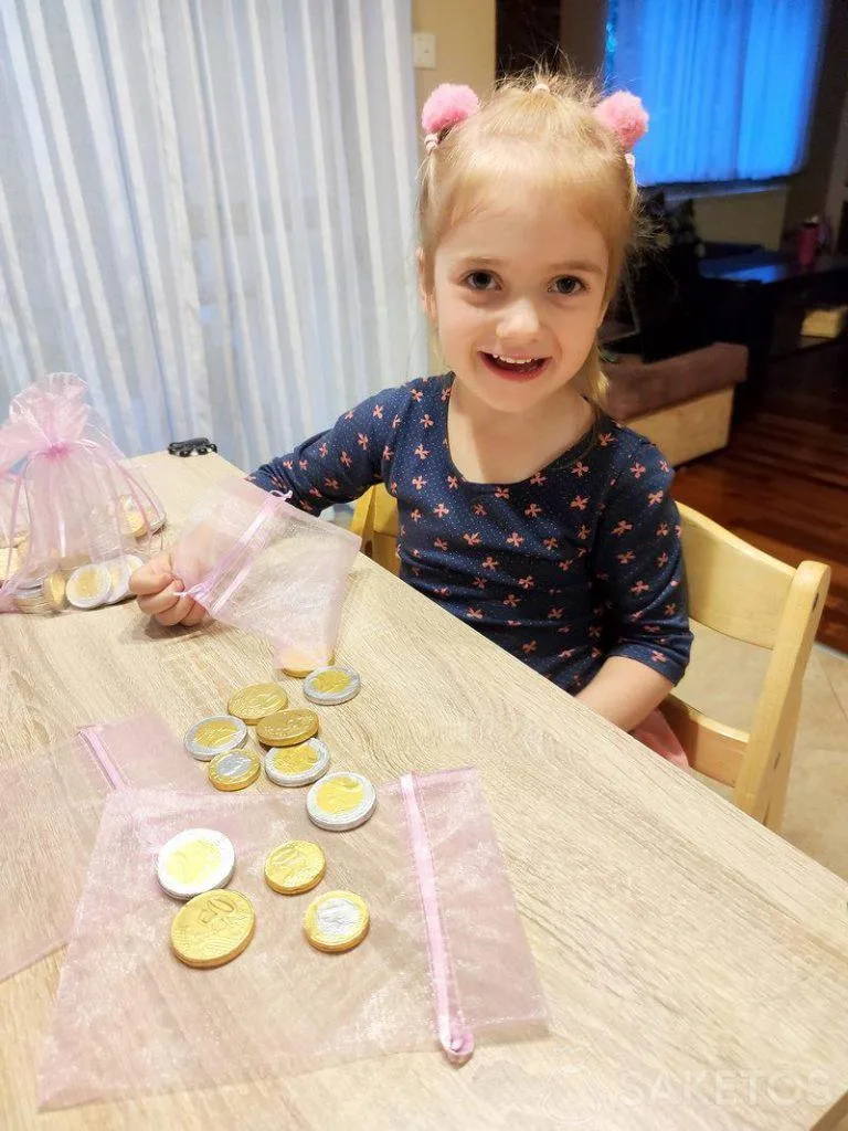 Une jeune fille remplit des sacs en organza avec des pièces de monnaie en chocolat.