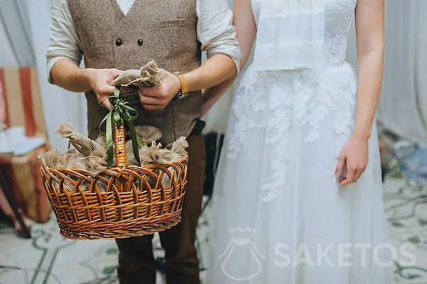 Mariée et marié avec des sacs de jute avec des cadeaux pour les invités du mariage.