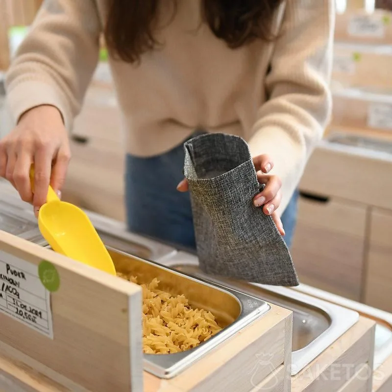 Une femme fait ses courses en mettant les produits en vrac dans des sacs de course durables - des emballages réutilisables en jute