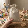 Sachets en lin tenus à la main avec fournitures créatives en arrière-plan