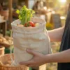 Sac en lin avec légumes frais et herbes tenu à la main dans un magasin bio